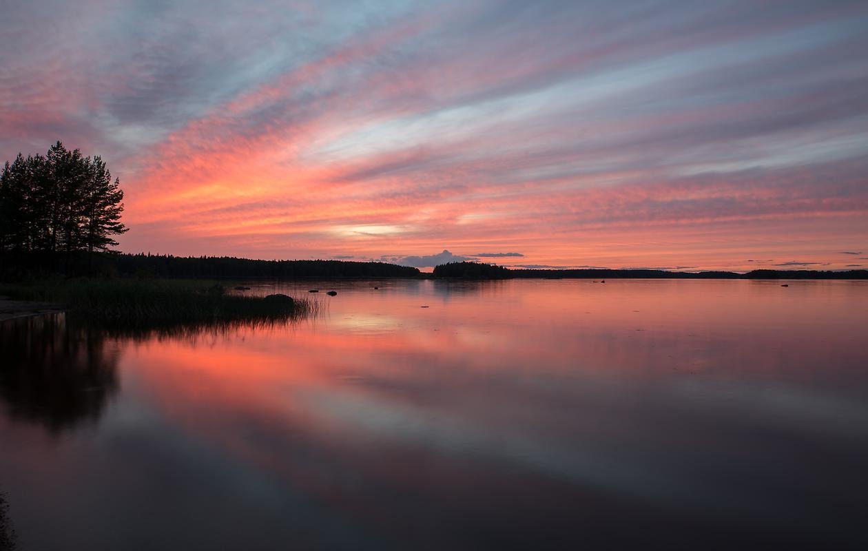 Solnedgång i Östa. Rosa himmel speglas i vatten.