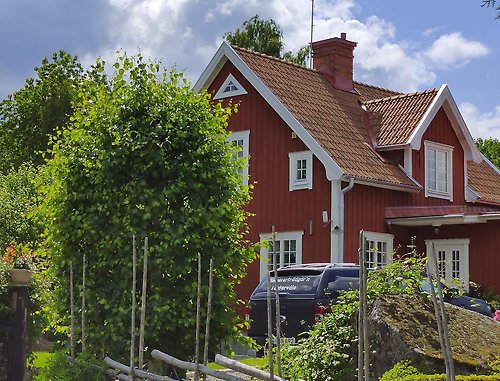 Rött hus med tegeltak, gärdesgård framför