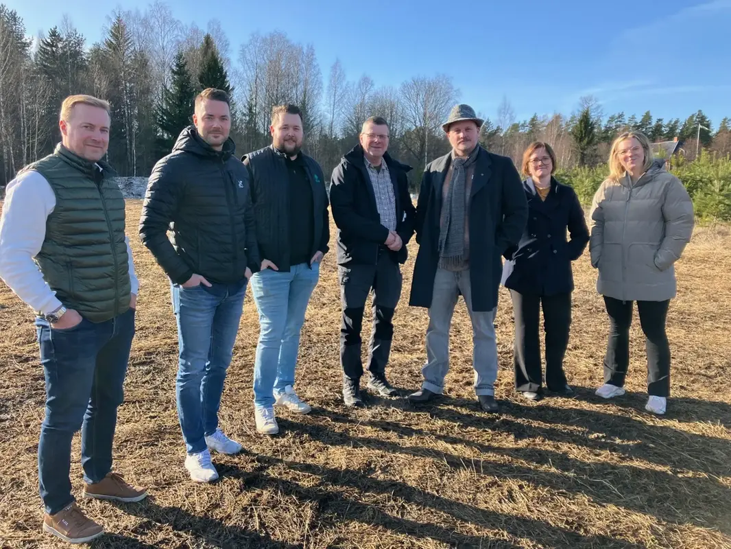Hela gruppen står vid de nya tomterna i solsken och ser glada ut.