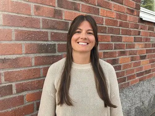 Moa Svensson är glad och står intill en tegelvägg