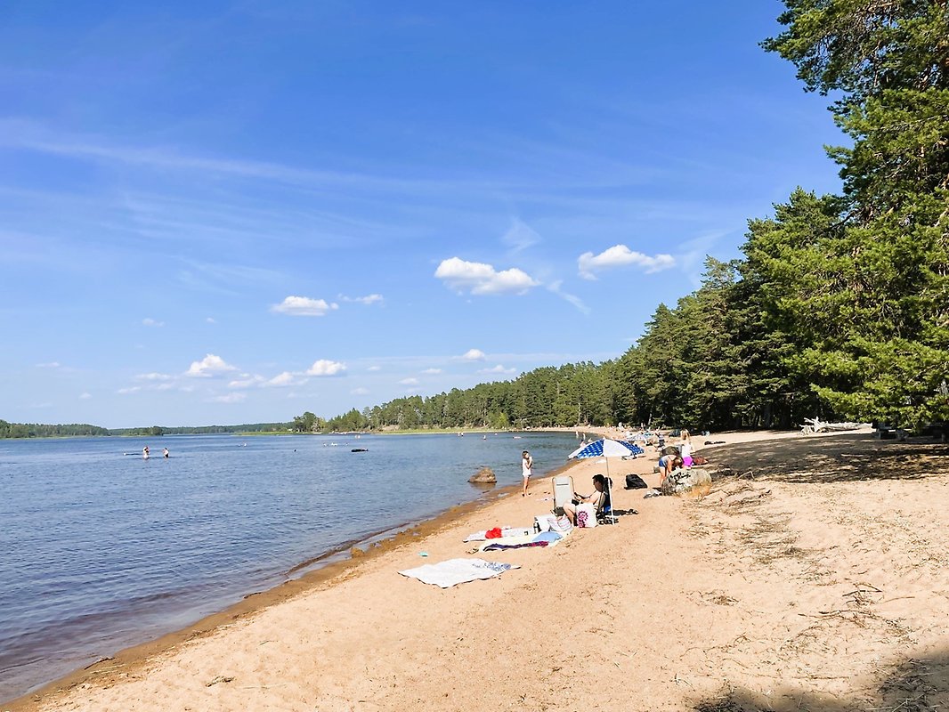 Lång sandstrand som det ligger människor på