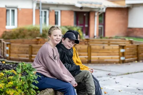 Tre ungdomar sitter ute på skolgården 