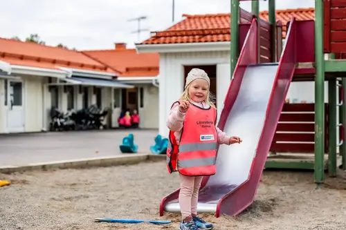 Förskoleflicka står framför rutschkana 